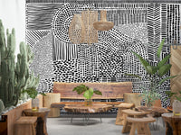 Black And White Maze wallpaper mural above a live-edge wood bench with cacti in a boho lounge