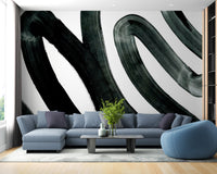 Black Brush Stroke wallpaper mural of bold black swirls on white behind a powder-blue sectional sofa in a living room