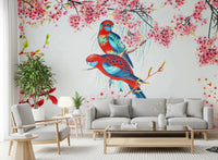 Blossom Birds wallpaper mural with red and blue parrots behind a grey sofa and wood armchair in a living room