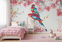 Blossom Birds wallpaper mural with colorful parrots behind a single bed with pink ruffled bedding in a kids room