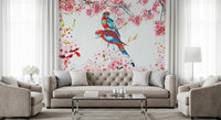 Blossom Birds wallpaper mural with red and teal parrots and pink blossoms behind a beige tufted sofa