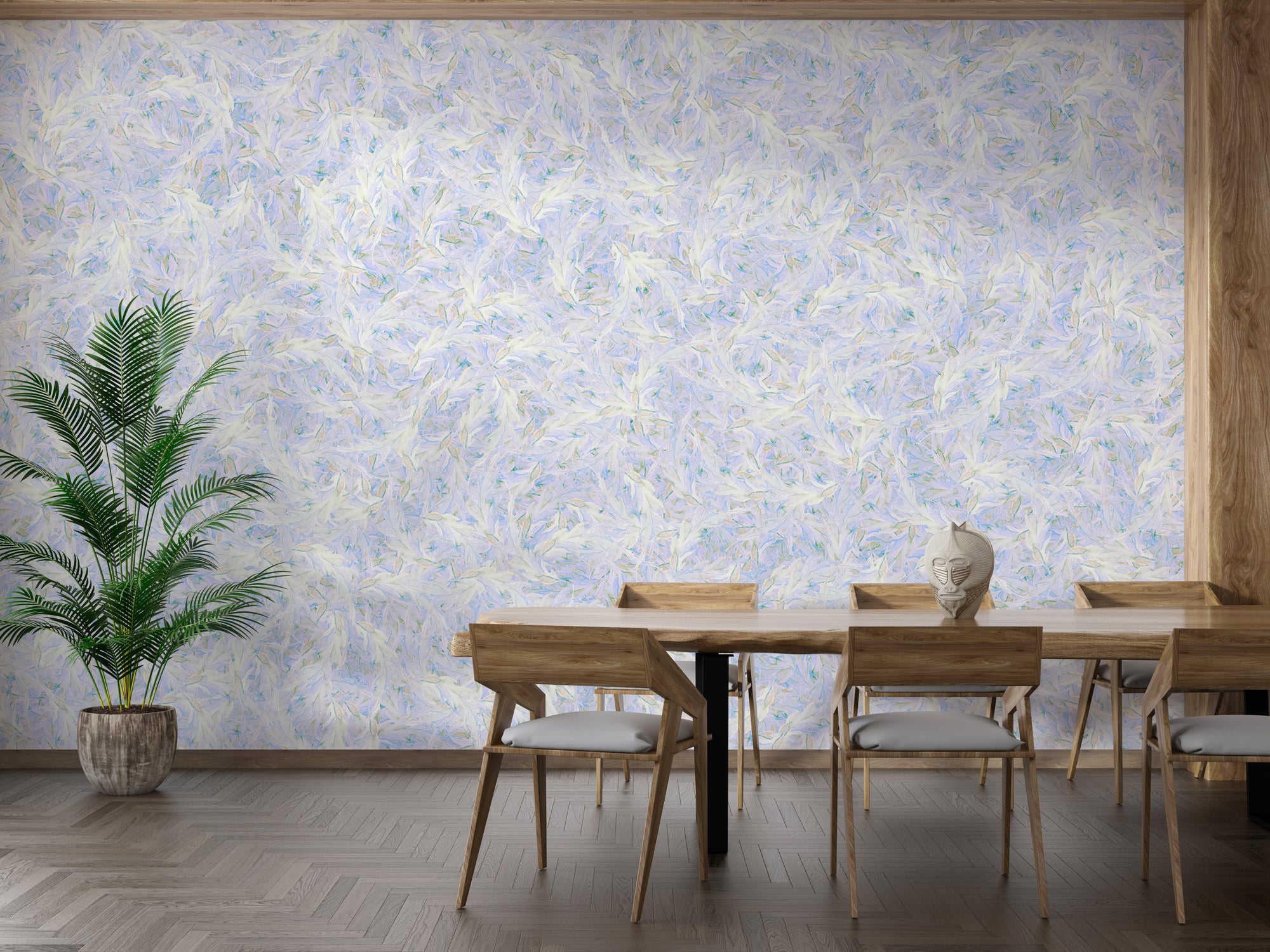 Blue Dancing Leaves Lila Azur wallpaper mural in a dining room with a wood table, cane chairs and palm plant