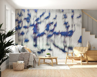 Flamingo Mirage wallpaper mural of blue flamingos behind a grey sofa and wood armchair in a bright living room