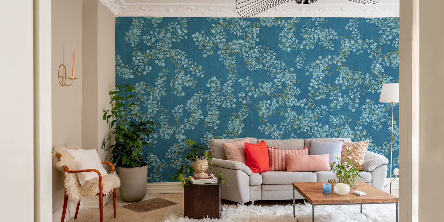 Blue Floral peel and stick wallpaper with white blossoms behind a gray sofa with coral pillows in a living room