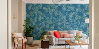 Blue Floral peel and stick wallpaper with white blossoms behind a gray sofa with coral pillows in a living room