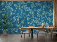 Blue Floral peel and stick wallpaper in teal with white blossoms behind a wooden dining table and chairs