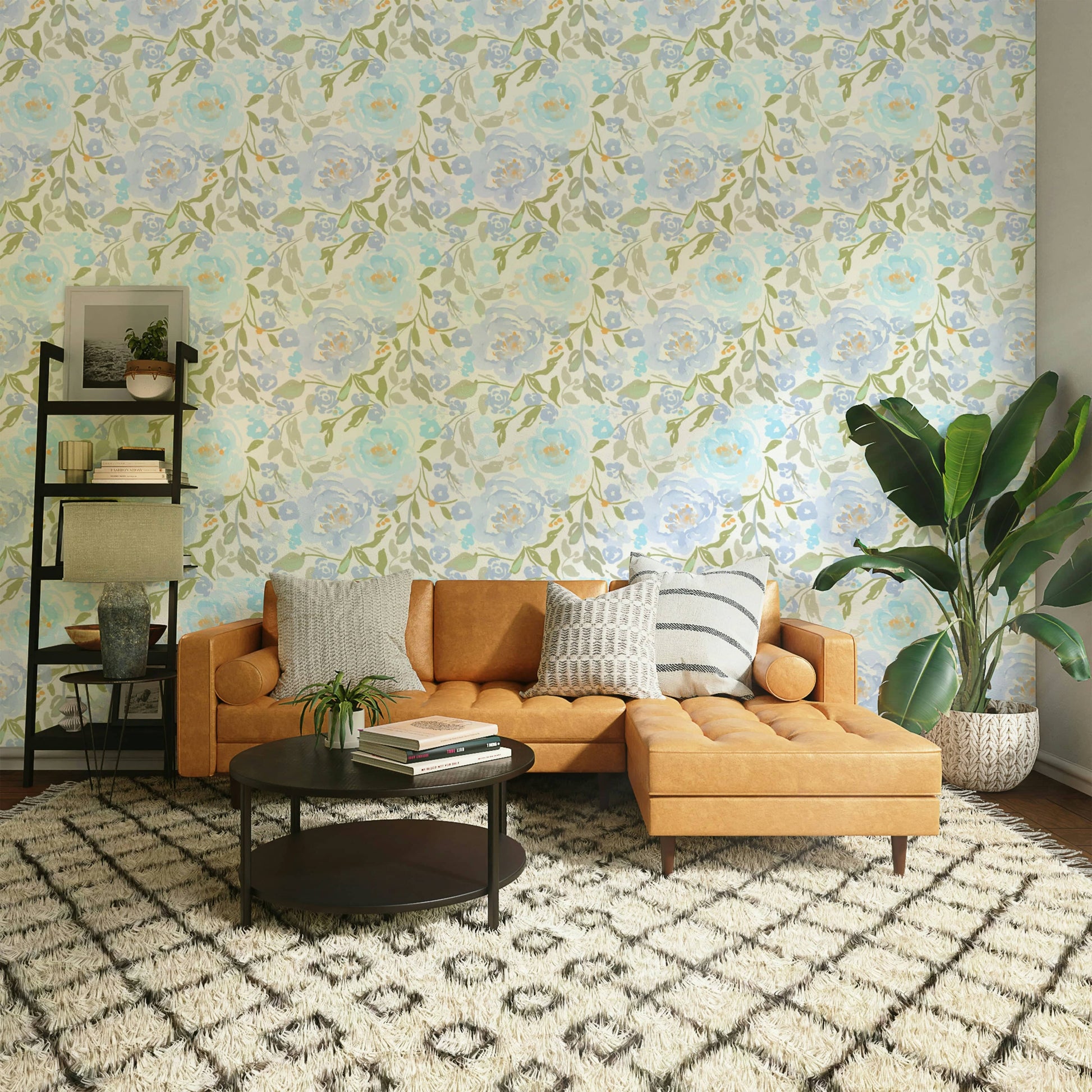 Watercolor Sky Blossom wallpaper in pale blue and sage floral tones behind a tan leather sectional sofa in a living room