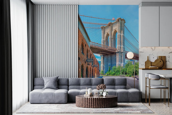 Brooklyn Bridge Vista wallpaper mural of the stone bridge tower and brick warehouse behind a grey sectional in a living room