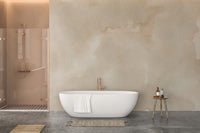 Abstract Beige Watercolor wallpaper mural of neutral wash behind a white freestanding tub and copper fixtures in a bathroom