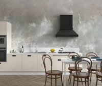 Baltic Sand Textured Abstract wallpaper mural in grey behind cream cabinets and a black range hood in a kitchen