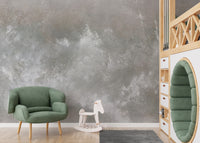 Baltic Sand Textured Abstract wallpaper mural in soft grey behind a green armchair and white rocking horse in a kids room