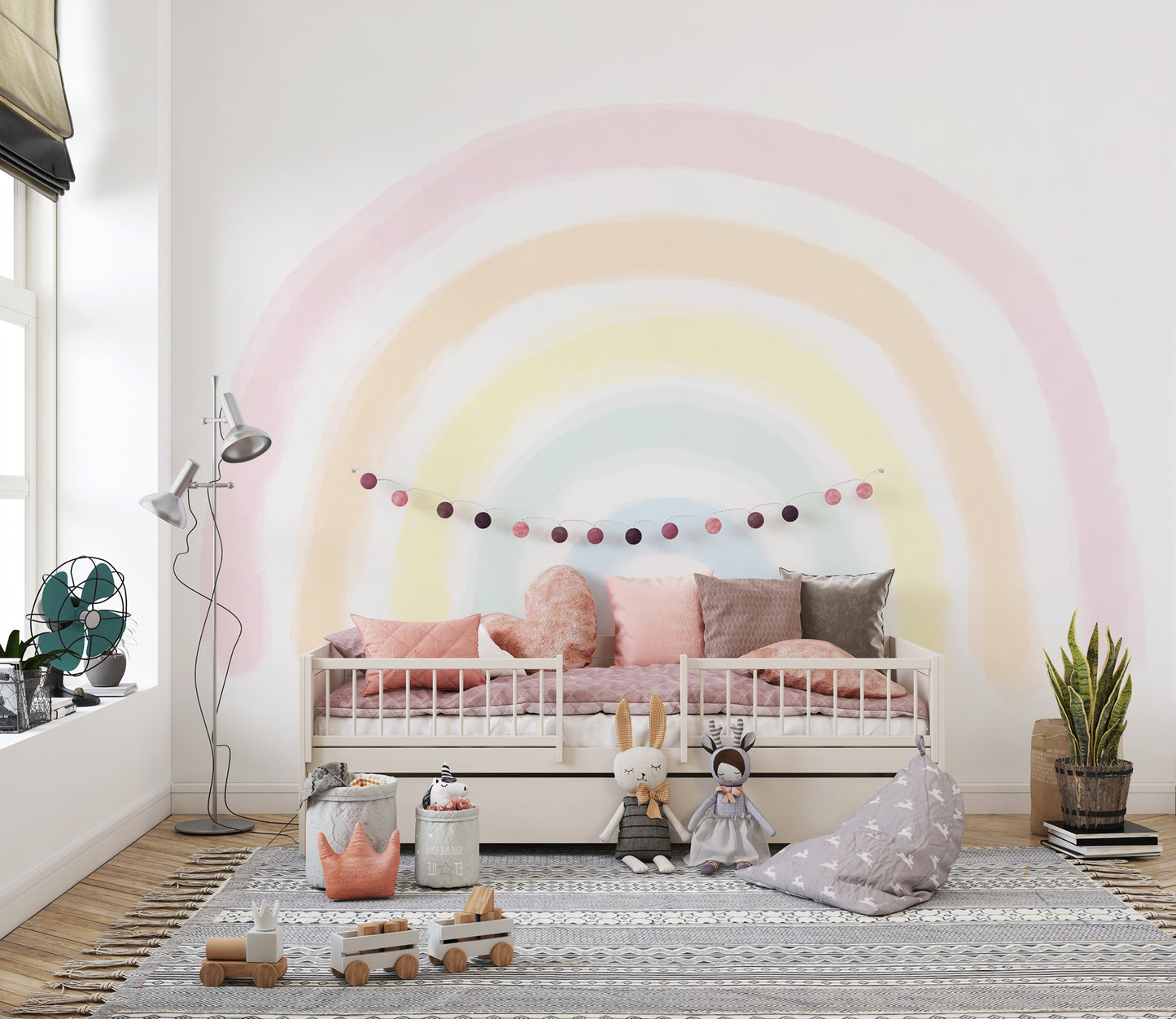 Pastel Rainbow wallpaper mural over a cream daybed with blush pillows, pom-pom garland and bunny plush in a kids room