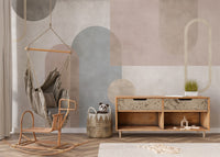 Serene Geometry wall mural of soft geometric shapes behind a hanging rattan swing chair and wooden sideboard