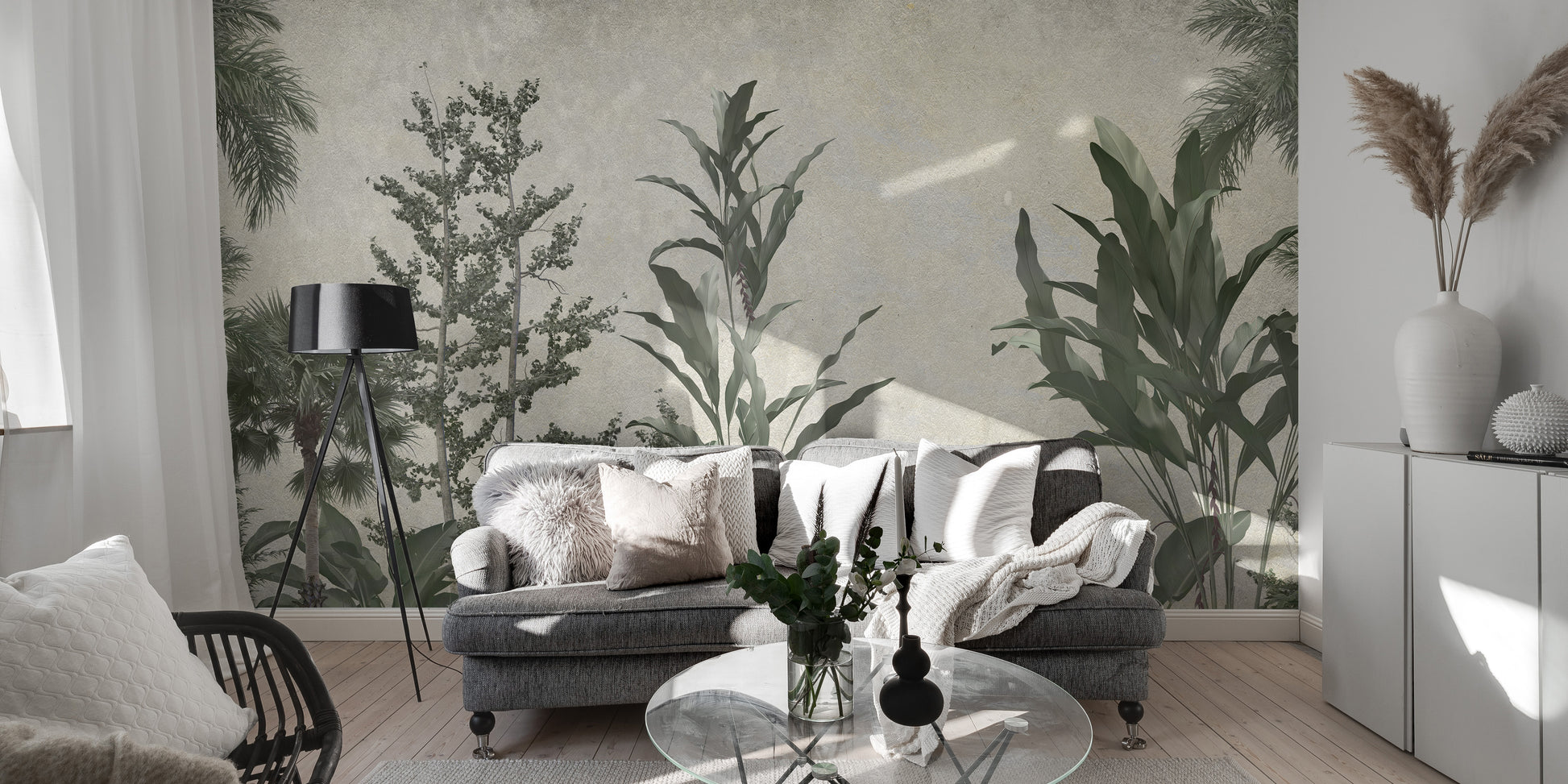 Verdant Valleys wallpaper mural of green trees and palms behind a grey sofa and black tripod floor lamp
