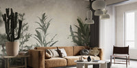 Verdant Valleys wallpaper mural of muted green foliage behind a tan leather sofa and tall potted cactus