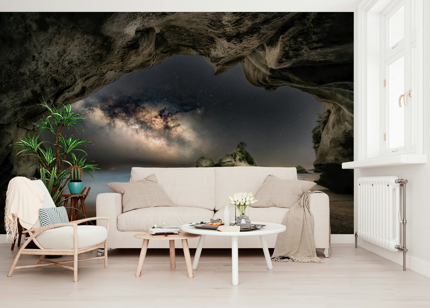 Cave Portal to Starlight wallpaper mural of a galaxy in a dark cave behind a cream sofa and rattan chair in a living room