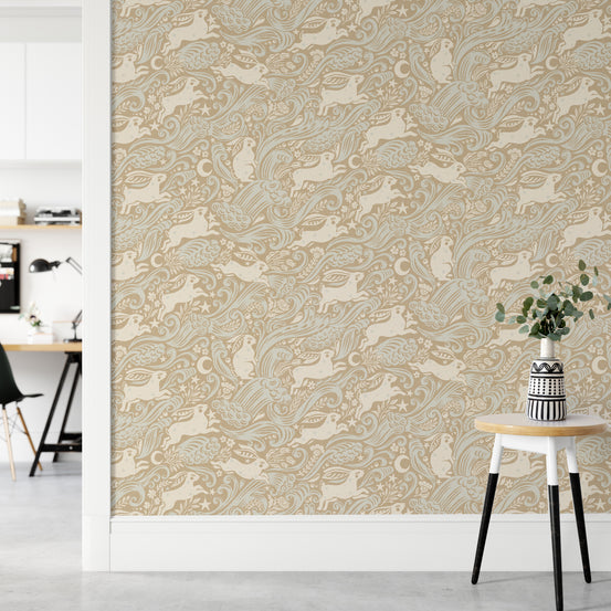 Celestial Sea Rabbit gold wallpaper of rabbits, birds and moons behind a white stool and patterned vase near a desk