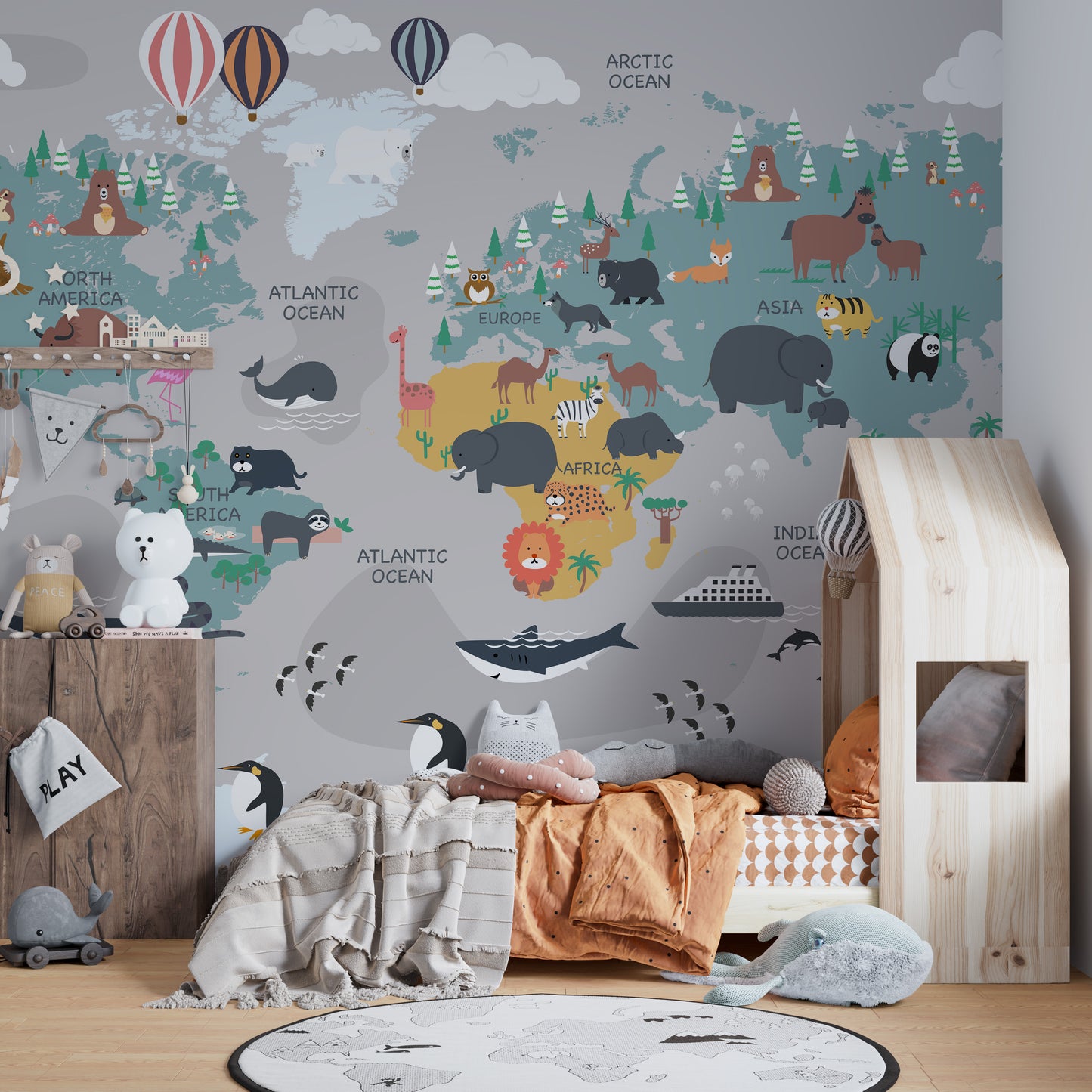 Children's World Map wallpaper full of animals beside a wood house-frame bed and penguin toys in a nursery