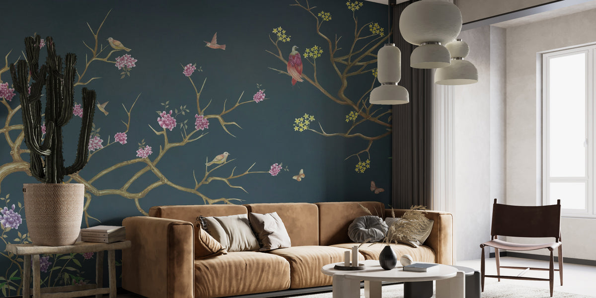 Flower Pattern Chinoiserie wallpaper with pink blossoms and birds on golden branches over deep navy behind a tan sofa