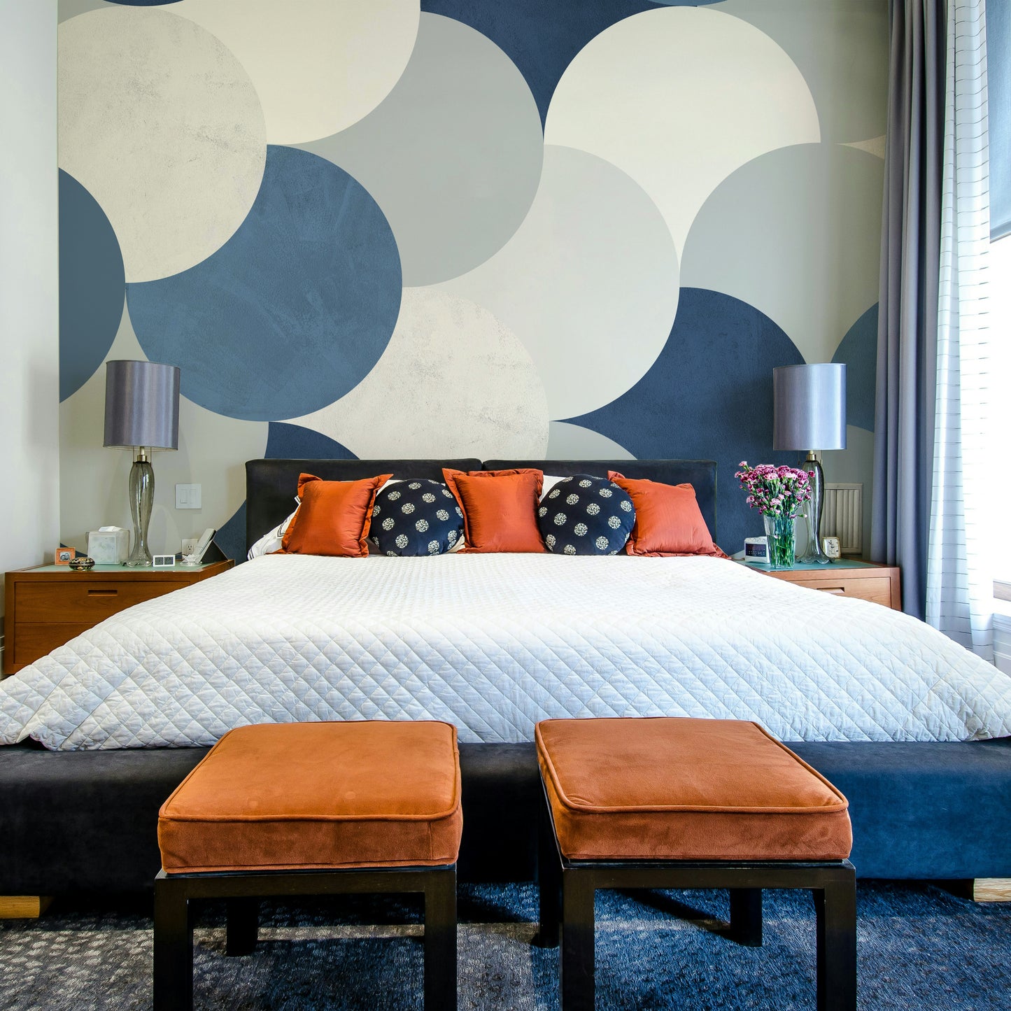 Circle Abstract wallpaper mural with blue and white circles above a black bed dressed with orange velvet stools