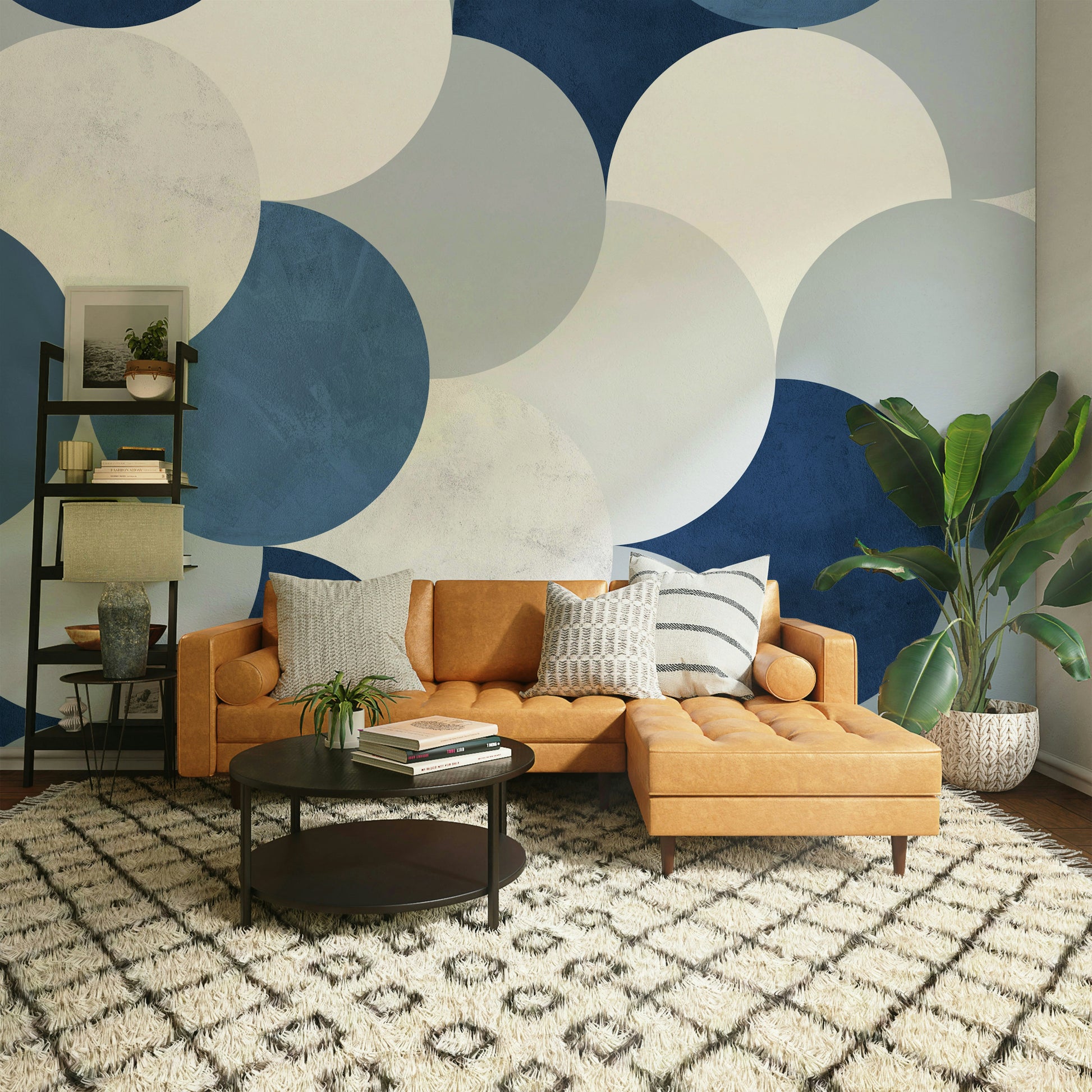 Circle Abstract wallpaper mural with navy and cream circles above a caramel leather sectional and palm