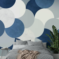 Circle Abstract wallpaper mural with blue and cream circles behind a gray bed and tall ZZ plant in a bedroom