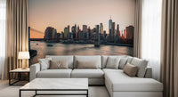 City Lights at Dawn wall mural of the glowing skyline behind a cream sectional sofa framed by beige curtains