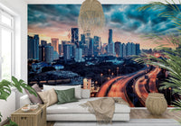 Cityscape Dawn wallpaper mural of skyscrapers and highway lights behind a white sectional and rattan pendant lamp