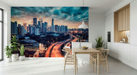 Cityscape Dawn wallpaper mural with teal clouds over the skyline behind a wood dining table and wishbone chairs