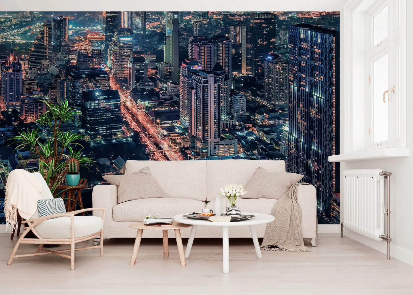 Cityscape Night wallpaper mural of a lit nighttime skyline behind a cream sofa and wood armchair in a living room
