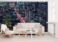Cityscape Night wallpaper mural of a lit nighttime skyline behind a cream sofa and wood armchair in a living room