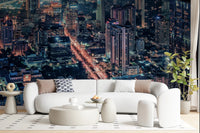 Cityscape Night wallpaper mural of a lit aerial skyline behind a white curved sofa and round ottomans
