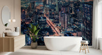 Cityscape Night wallpaper mural of an illuminated skyline in a bathroom with a freestanding white tub and plant