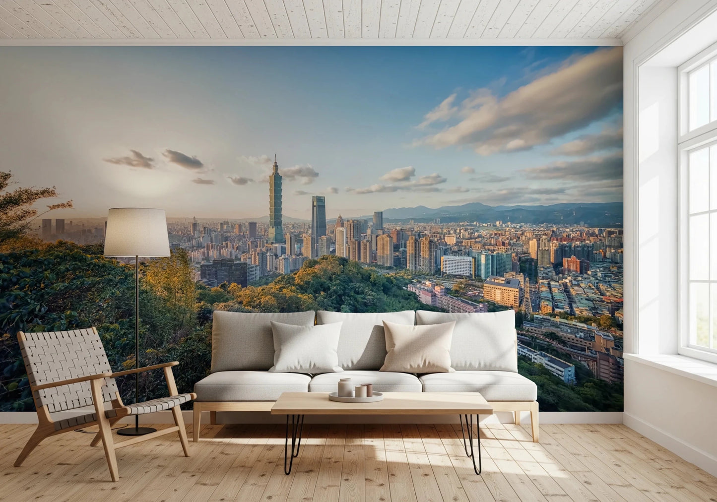 Cityscape Vista wallpaper mural of the Taipei skyline above a grey sofa piled with knit and orange pillows