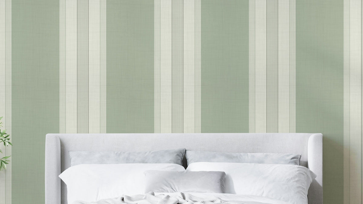 Classic Multiline Stripes Sage Green wallpaper behind a grey upholstered headboard in a soft bedroom