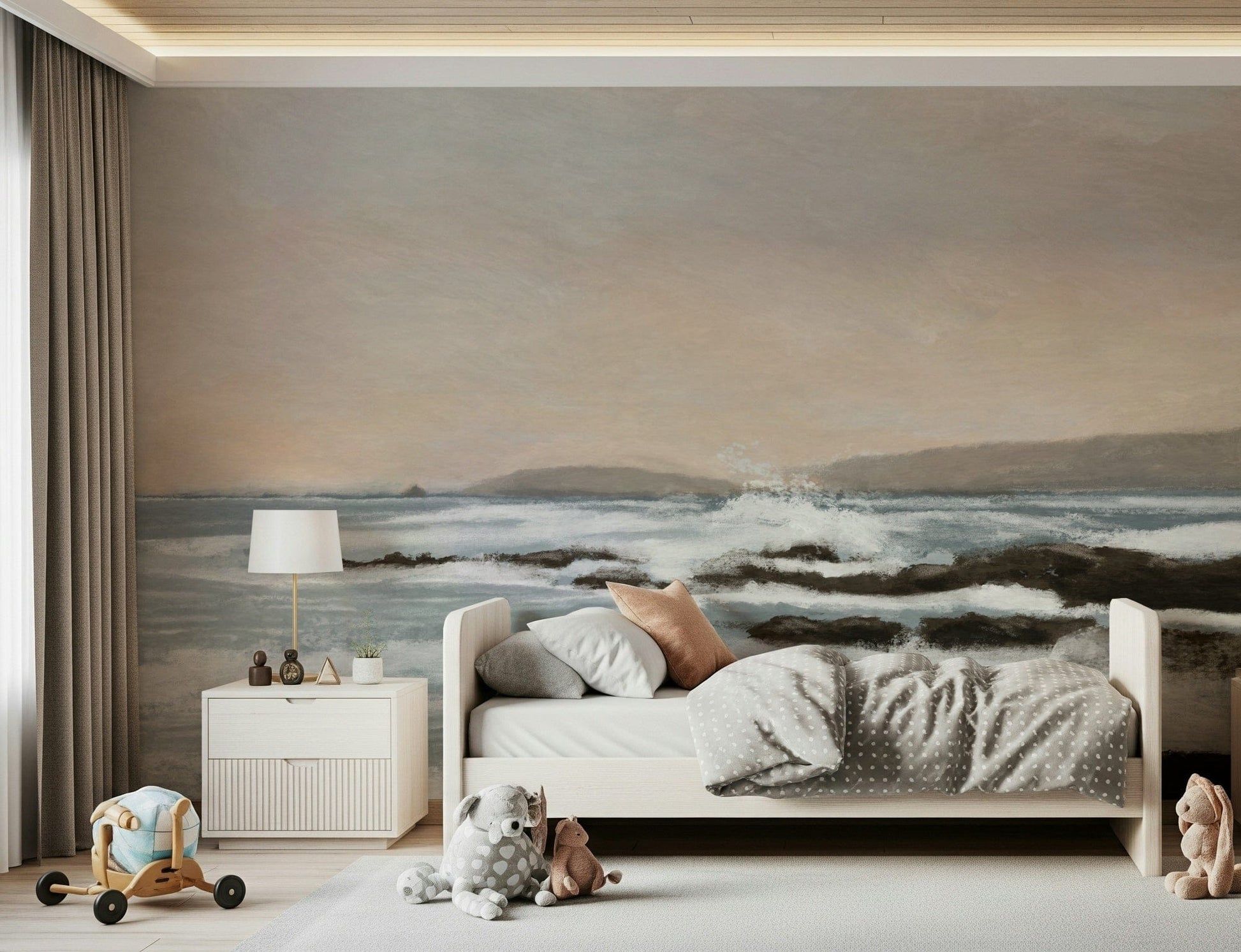 Coastal Hues wallpaper mural of blue waves over rocks behind a white bed with a polka-dot duvet in a kids room