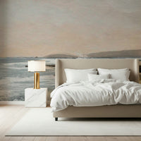 Coastal Hues wallpaper mural of a pale blue seascape behind a beige upholstered bed with white bedding in a bedroom