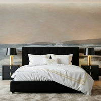 Coastal Hues wallpaper mural of a calm shore behind a black headboard bed with gold-trim bedding in a bedroom