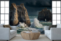Coastal Giants wallpaper mural of crashing waves on sea stacks behind two white armchairs and a wood drum table