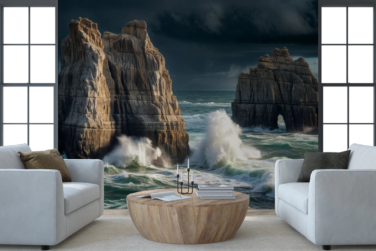 Coastal Giants wallpaper mural of crashing waves on sea stacks behind two white armchairs and a wood drum table