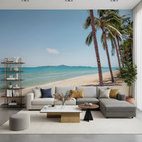 Coastal Palm Serenity wallpaper mural with tall palms and turquoise sea behind a gray sectional and open shelving