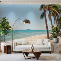 Coastal Palm Serenity wallpaper mural of a turquoise shore behind a white sofa and chrome arc lamp in a living room