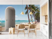 Coastal Palm Serenity wallpaper mural of sea and palms by a wood dining table and arched doorway in an open kitchen