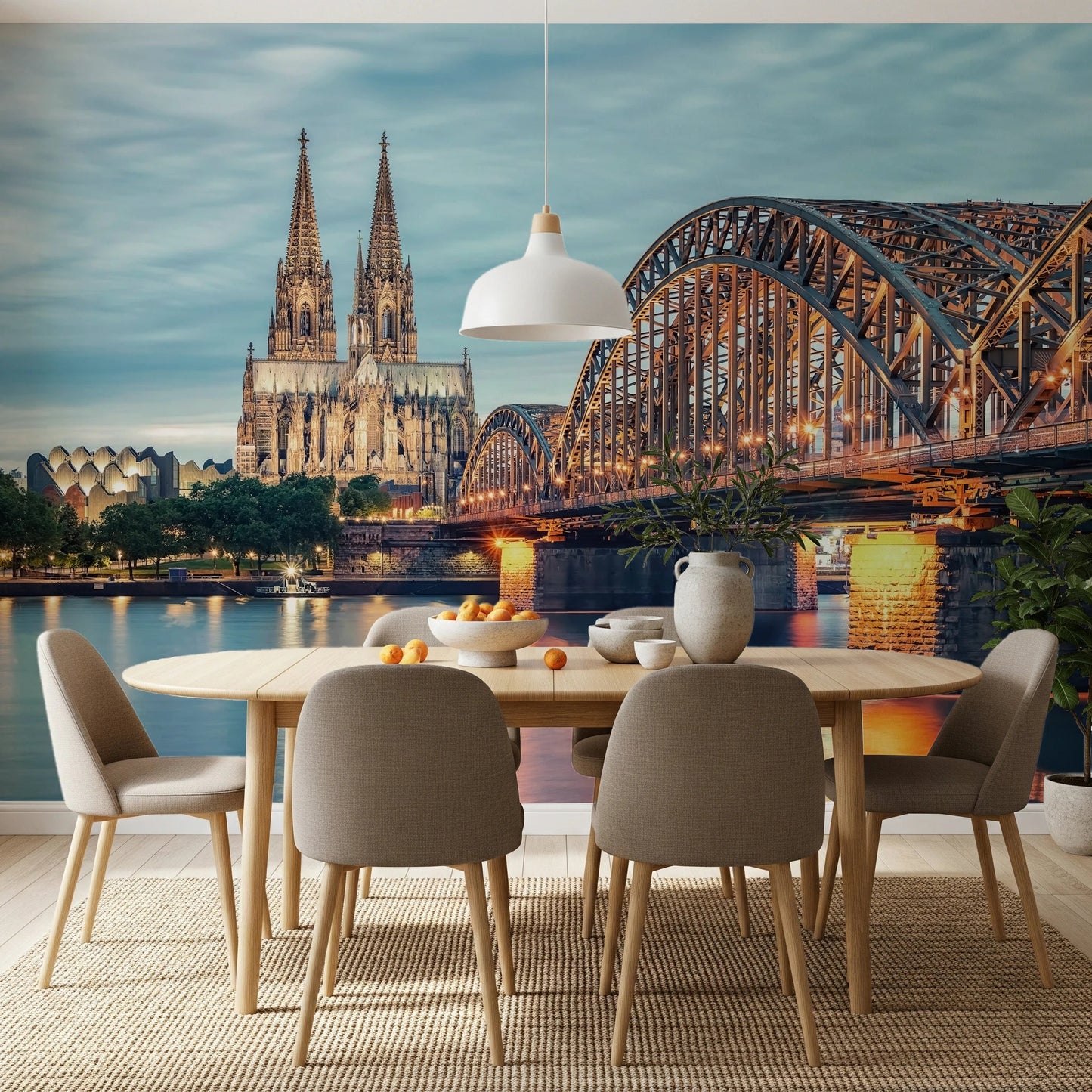 Cologne at Dusk wallpaper mural with the cathedral and glowing bridge behind an oval dining table and beige chairs