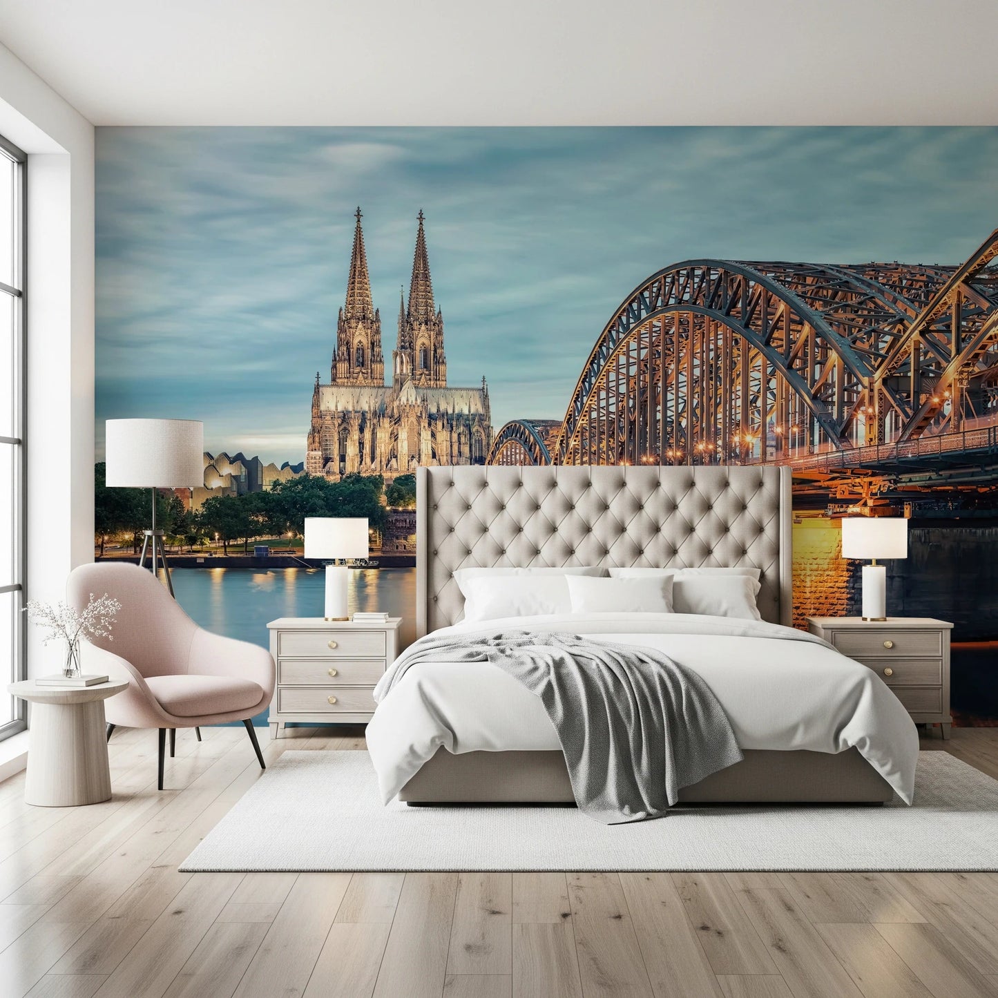 Cologne at Dusk wallpaper mural of the cathedral at twilight above a tufted bed and pink accent chair in a bedroom