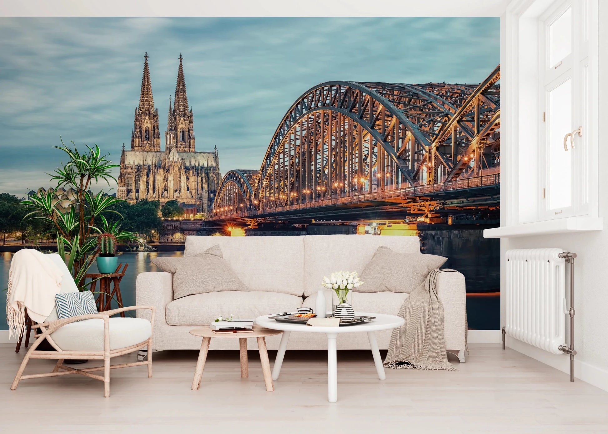 Cologne at Dusk wallpaper mural showing the lit bridge and cathedral above a cream sofa and wooden armchair in a living room