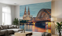 Cologne at Dusk wallpaper mural with the cathedral and bridge reflected in the Rhine above a grey sectional in a living room