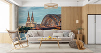 Cologne at Dusk wallpaper mural of the Rhine bridge and cathedral behind a grey sofa and rocking chair in a living room