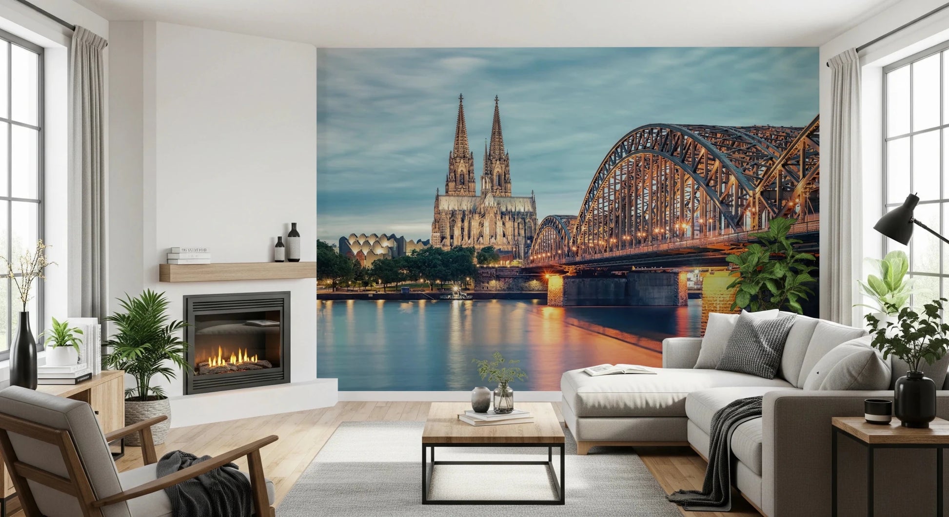 Cologne at Dusk wallpaper mural of the Rhine, bridge and cathedral beside a lit fireplace and grey sectional sofa