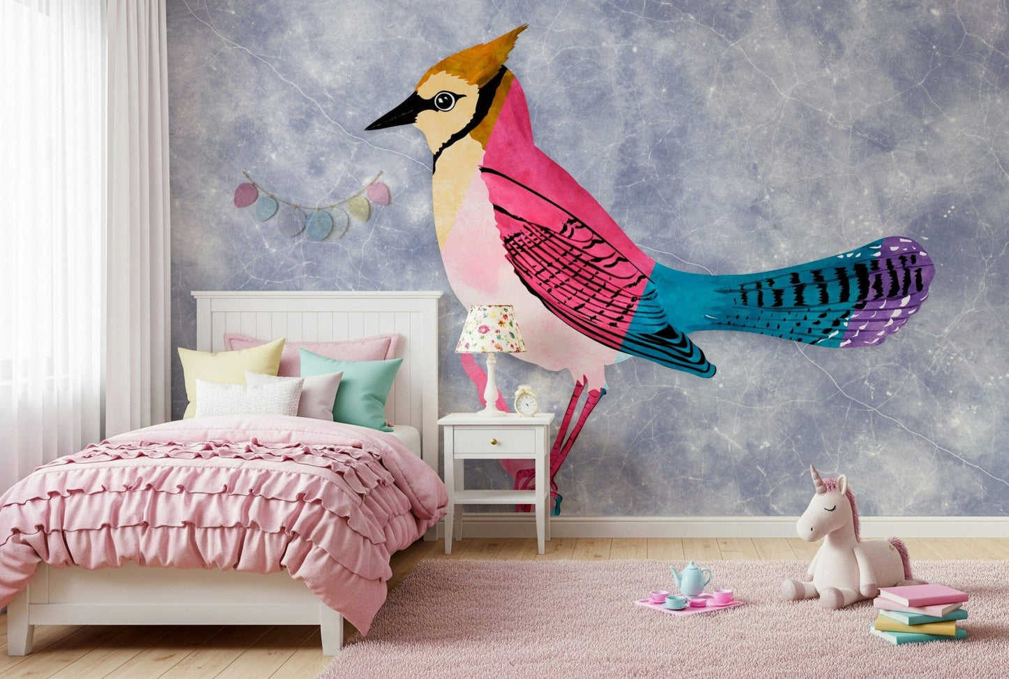 Colorful Jay wall mural in pink and blue behind a white ruffled bed and unicorn plush in a girls bedroom